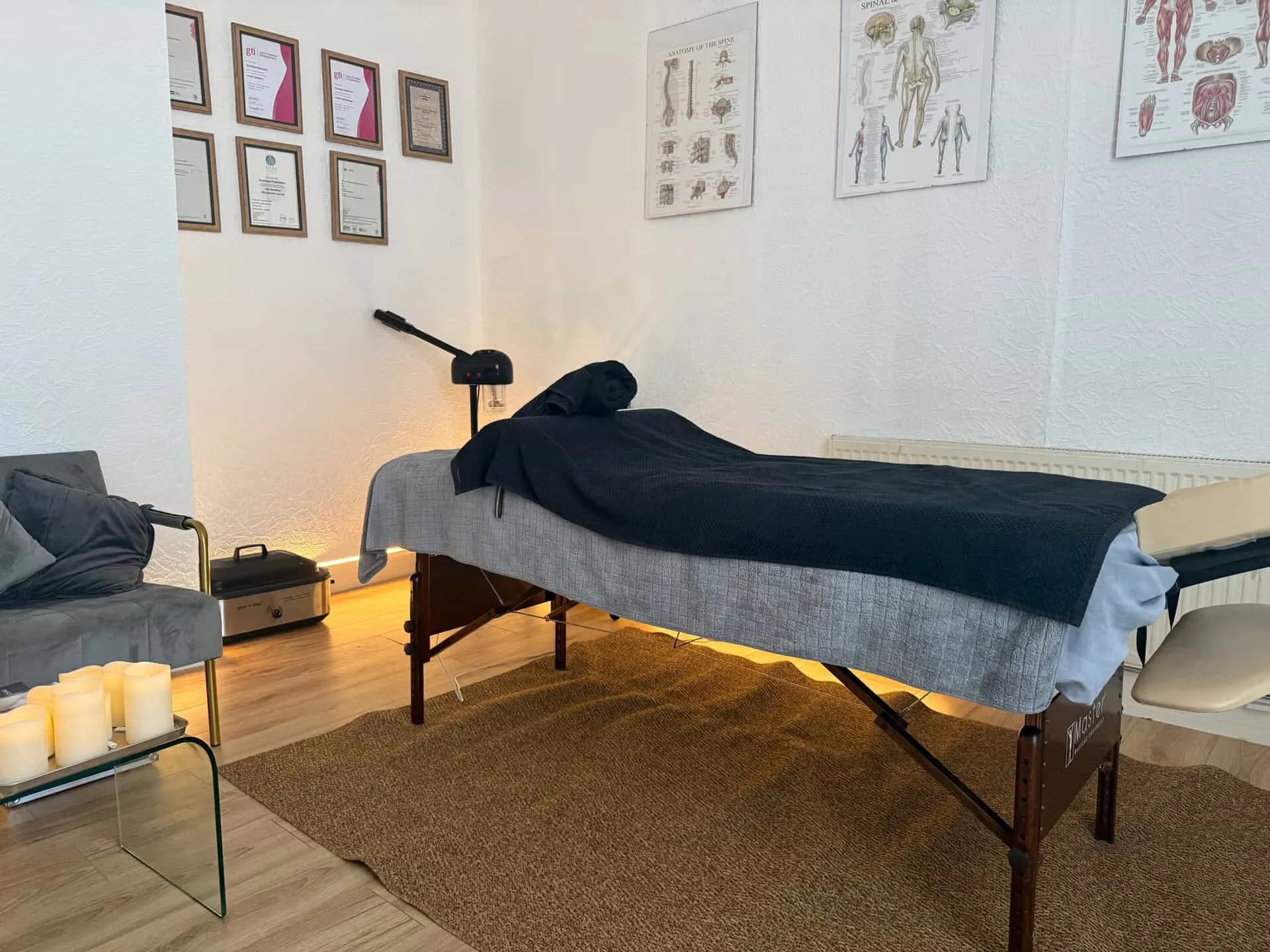Massage table with warm under-lighting, candles and anatomy posters in the Prescot studio